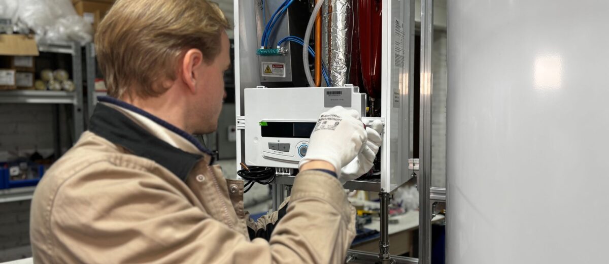Technician installing or repairing a heating system in an indoor workshop setting.