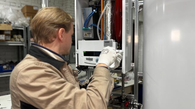 Technician installing or repairing a heating system in an indoor workshop setting.