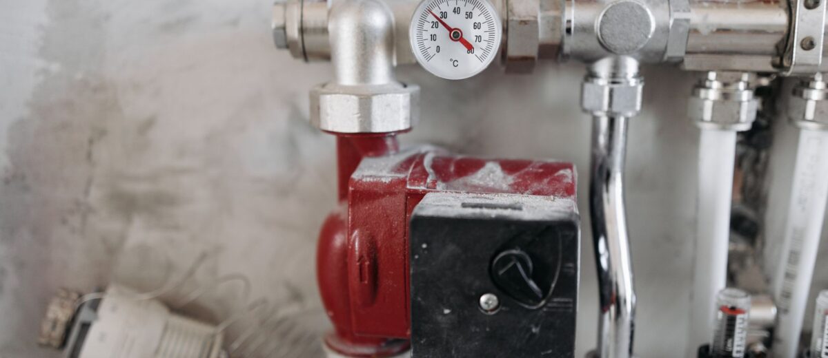 Close-up view of an industrial plumbing system featuring a pressure gauge and steel pipes.