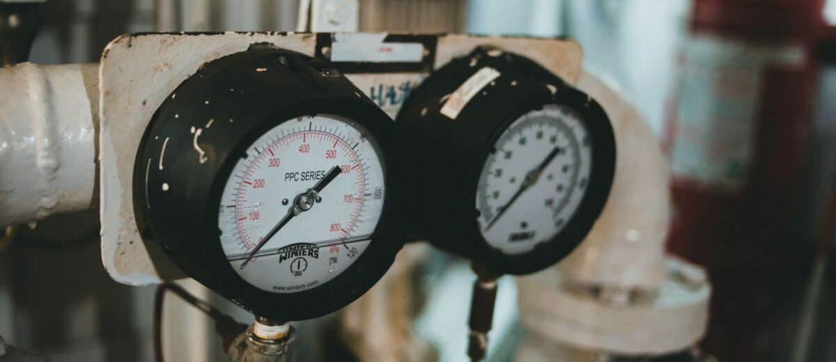 Detailed close-up of industrial pressure gauges set against a blurred machine background.