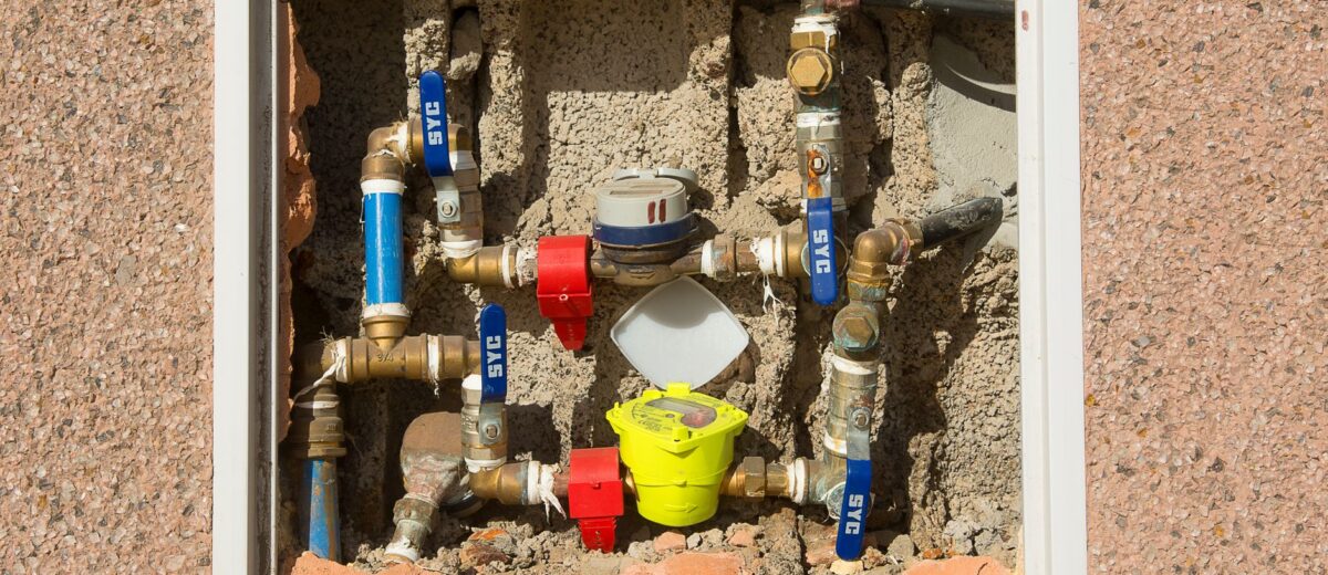 Detailed view of a complex water meter setup embedded in a concrete wall.