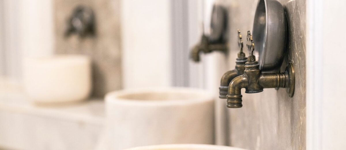 Close-up of vintage Turkish bath faucets with marble basins, showcasing traditional design.