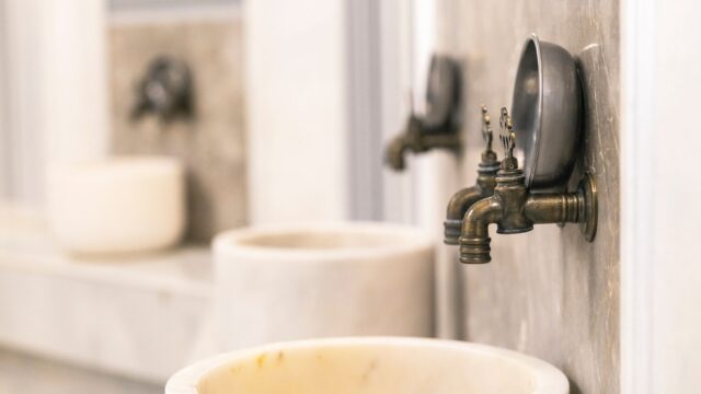 Close-up of vintage Turkish bath faucets with marble basins, showcasing traditional design.