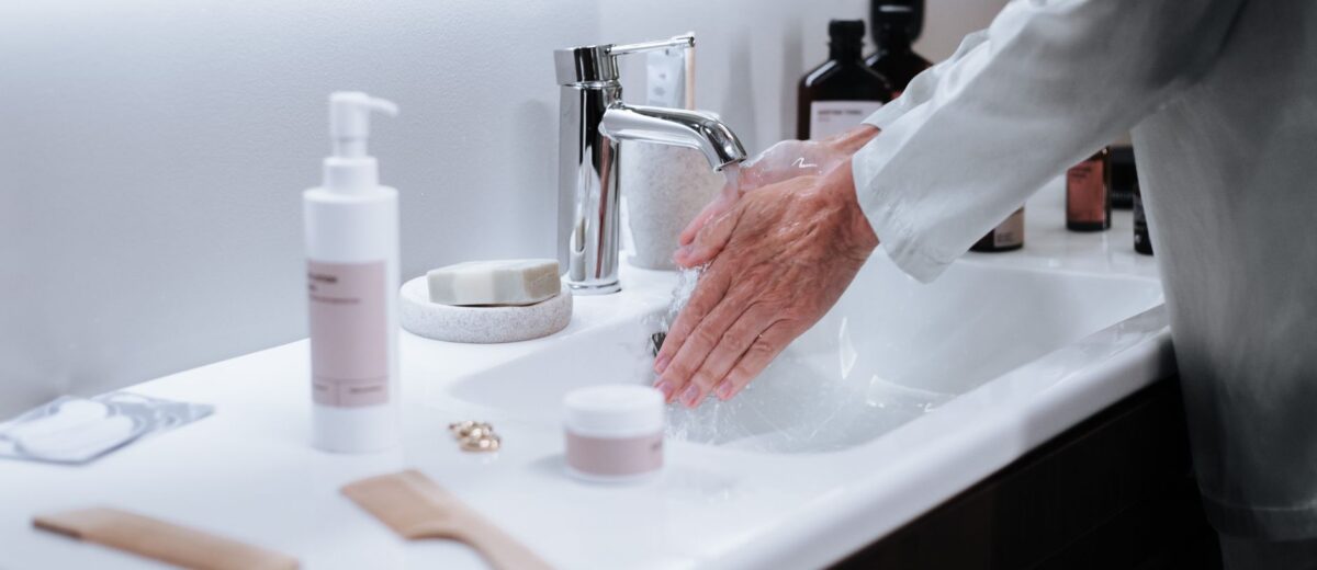Close-up of a man washing hands in a modern bathroom, emphasizing hygiene and cleanliness.